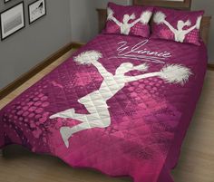 a bed with a pink comforter that has a cheerleader on it and white writing