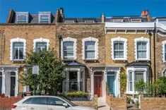 a white car parked in front of a row of brick townhouses on a sunny day