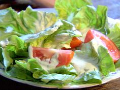 lettuce and tomato salad on a plate with dressing in the middle, ready to be eaten