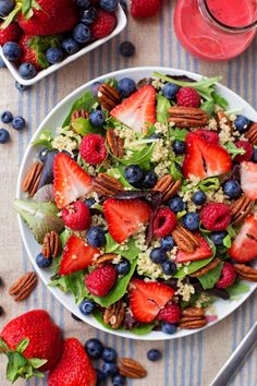 a salad with strawberries, blueberries and pecans