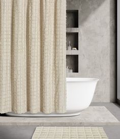 a bath tub sitting next to a white rug on top of a bathroom floor with a shower curtain