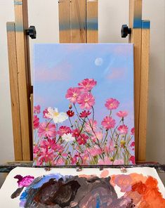 an easel with paint and flowers on it