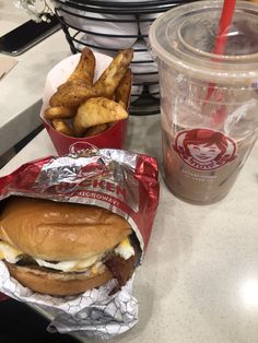 there is a sandwich and fries on the table next to a cup of sodas