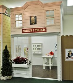 a doll house with furniture and decorations on display in the front room, as well as an artificial tree