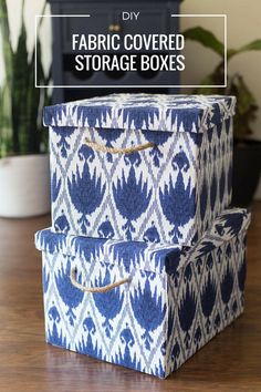 three fabric covered storage boxes sitting on top of a wooden table next to a potted plant