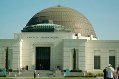 people are standing in front of a large building with a dome on it's roof