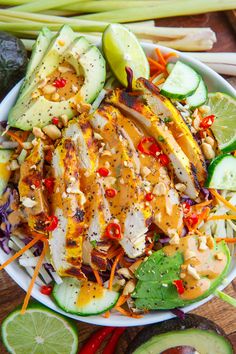 a salad with chicken, cucumbers, carrots and other vegetables on a wooden table