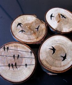 four pieces of wood with birds painted on them sitting on top of each other in front of a black table