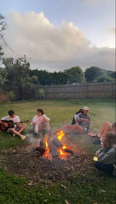 four people sitting around a campfire playing guitar