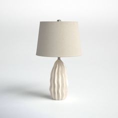 a white lamp with a beige shade on it's base and a light bulb in the middle