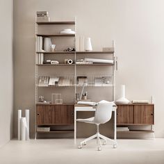 a white chair sitting in front of a desk with bookshelves and shelves on it