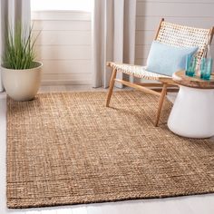 a living room area with a chair, rug and potted plant on the floor