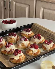 a tray filled with croissants covered in icing and raspberries