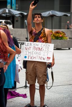 a man holding up a sign while standing in front of other people on the street