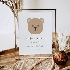 a sign with a bear on it sitting next to a vase and some dry grass