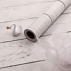 a pair of ear buds sitting on top of a white wooden floor next to a rolled up piece of paper