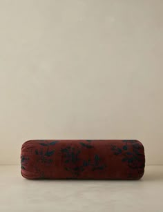 a red and blue pillow sitting on top of a white floor next to a wall