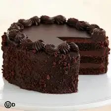 a chocolate cake on a white plate with one slice cut out and ready to be eaten