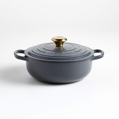 a round casserole with a golden lid on a white background, it is made from cast iron