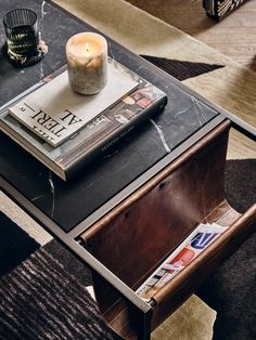 a coffee table with a magazine on it and a candle sitting on top of it