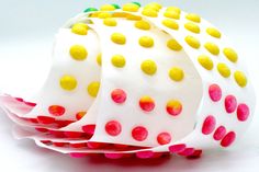 a white and yellow polka dot cake sitting on top of a pink paper wrapper