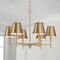 a gold chandelier with five lamps hanging from it's sides in a living room