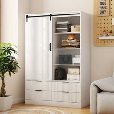 a living room with a white armoire next to a potted plant