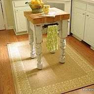 a kitchen with white cabinets and wood floors is pictured in this image, there are yellow flowers on the table