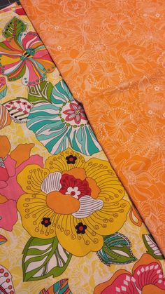 two orange and yellow floral fabric laying next to each other