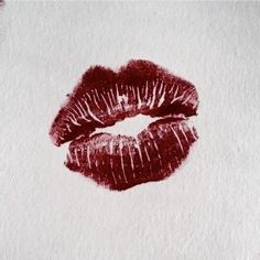 a close up of a red lipstick on a white paper with watermarked lips