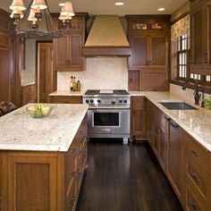 a kitchen with wooden cabinets and an island in the middle is lit by pendant lights