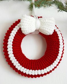 a red and white knitted christmas ornament hanging from a tree