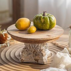 two lemons and three oranges sitting on a wooden table with other fruit in the background