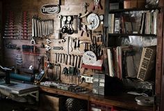 a room filled with lots of tools and assorted items hanging on the wall next to a desk