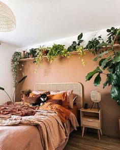 a bed in a bedroom with plants on the wall and a cat laying on it