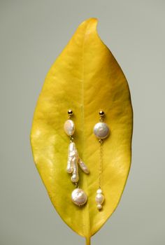 a yellow leaf with some pearls hanging from it's end and on the other side