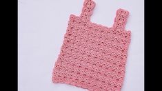 a pink crocheted bag sitting on top of a white surface