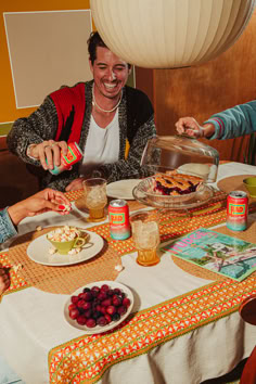 three people sitting at a table with food and drinks