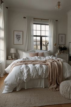 a bed with white sheets and blankets in a bedroom next to a window, rugs on the floor