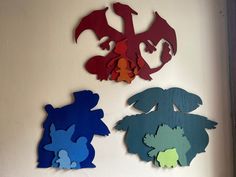 three pieces of cut out paper are hanging on the wall next to each other with different shapes and colors