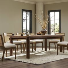 a dining room table with chairs and a bowl of fruit on the table next to it