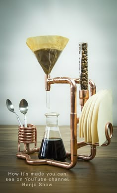 an image of a coffee maker made out of copper pipes and other items on a wooden table