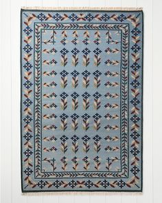 a blue rug with an arrow design on the front and back side, hanging from a white wall