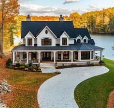 a large white house sitting next to a body of water in the middle of autumn