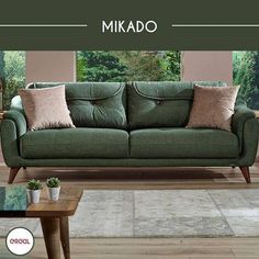 a green couch sitting on top of a hard wood floor next to a coffee table