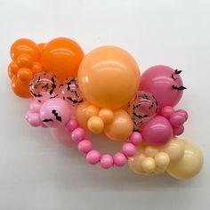 an assortment of balloons are arranged on a white surface, including orange and pink ones