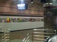 an empty subway station with metal handrails and graffiti on the wall behind it