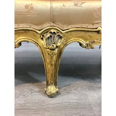 an ornately decorated bench with gold paint and wood trimmings on the legs