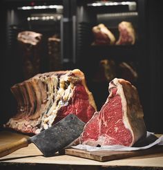 two pieces of raw meat sitting on top of a cutting board next to a knife