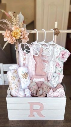 a baby's gift box with clothes and flowers on it, sitting on a table